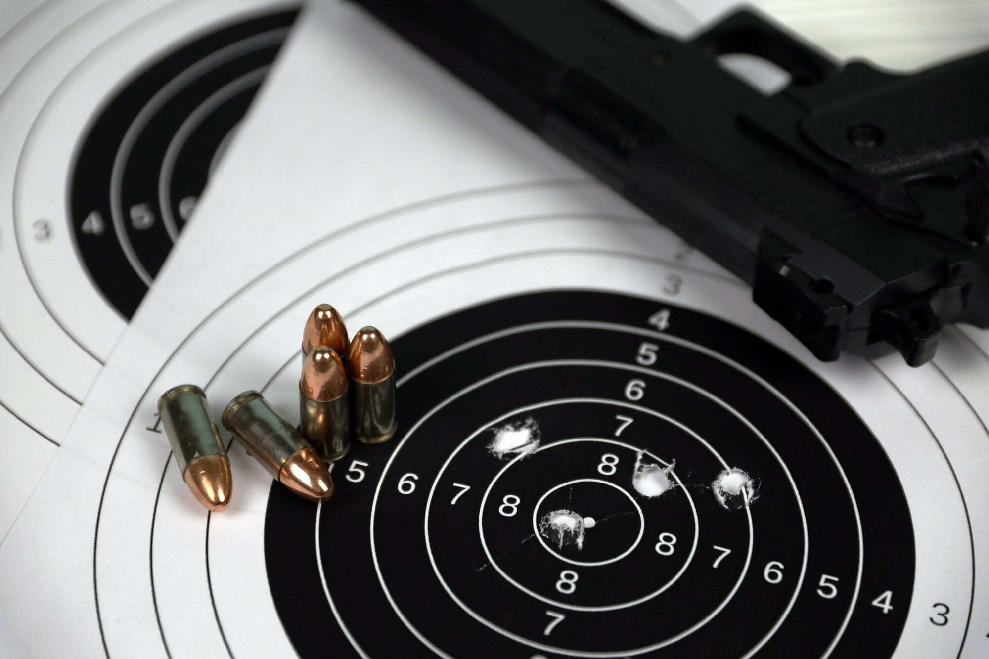 gun-and-many-bullets-shooting-targets-on-white-table-in-shooting-range-polygon-training-for-aiming.jpg